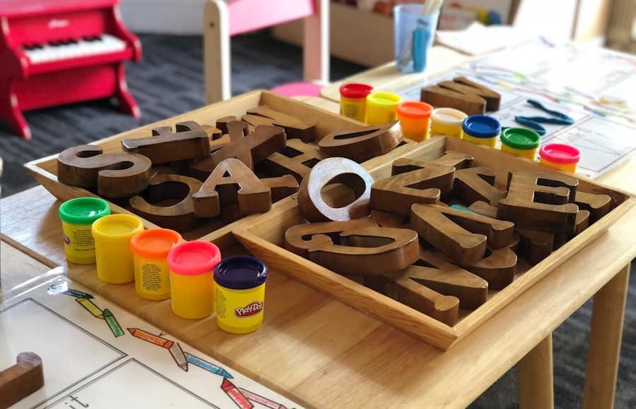 A preschool play table with wooden toys and pots of paint.