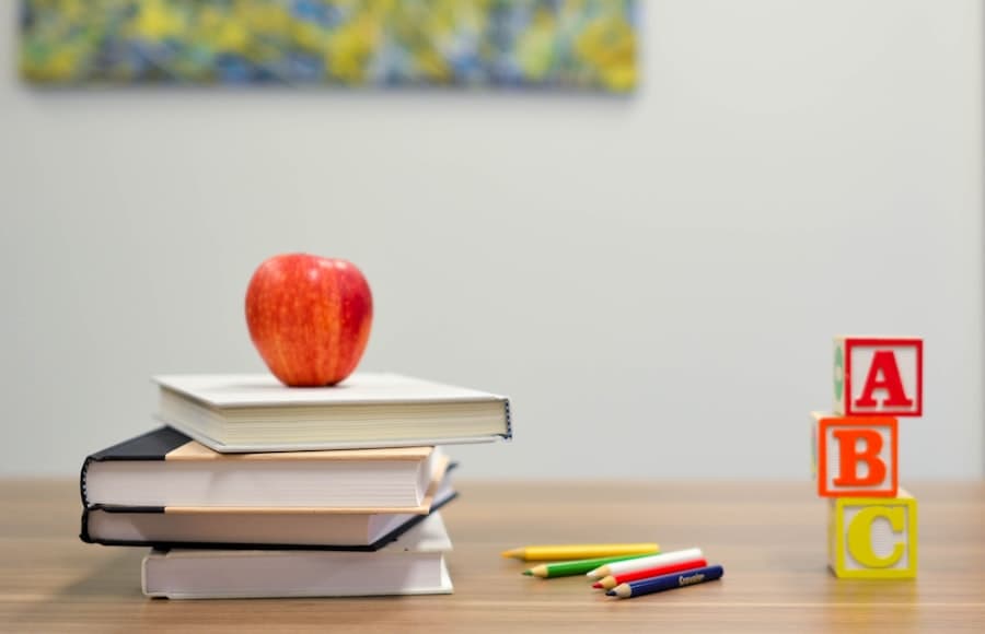 An apple resting on a stack of books beside alphabet blocks.