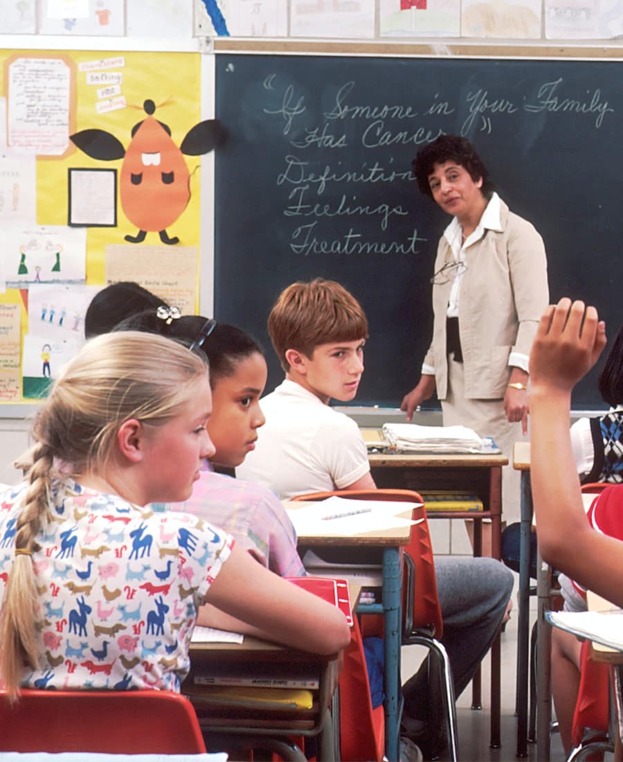 A teacher reading aloud to a small group of young children in a classroom.